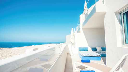 Terassi, jossa aurinkotuoleja ja merinäkymä. (Tekoälyn luoma teksti)