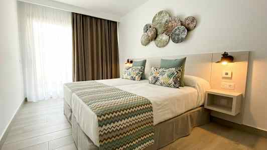 Makuuhuone, jossa on parivuode, koristeelliset tyynyt ja koristeltu pääty. (Tekoälyn luoma teksti)