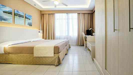 Hotellihuone, jossa on parisänky, työpöytä ja kattotuuletin. (Tekoälyn luoma teksti)