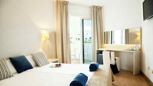 Hotellihuone kahdella yhden hengen vuoteella, parvekkeella ja työpöydällä. (Tekoälyn luoma teksti)