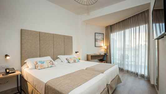 Moderni hotellihuone, jossa on parivuode, työpöytä ja parveke. (Tekoälyn luoma teksti)