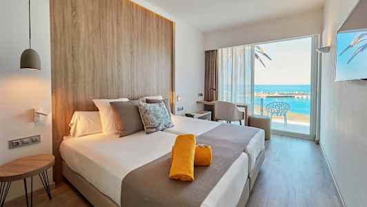 Moderni hotellihuone, josta on näkymä merelle suuren lasioven kautta. (Tekoälyn luoma teksti)