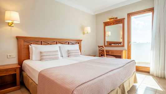 Kahden hengen huone, jossa puukalusteet ja näkymä aurinkoiselle parvekkeelle. (Tekoälyn luoma teksti)