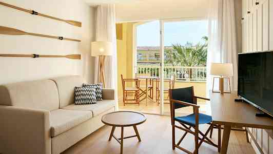 Huone, jossa sohva, pöytä ja tuoleja. Ovi johtaa parvekkeelle, jolta on näkymä. (Tekoälyn luoma teksti)