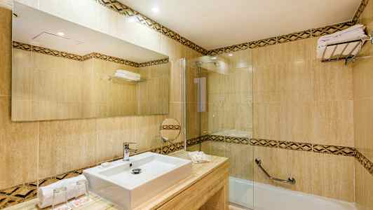 Moderni kylpyhuone, jossa on laattoja, suorakulmainen pesuallas, suuri peili ja kylpyamme lasiseinällä. (Tekoälyn luoma teksti)