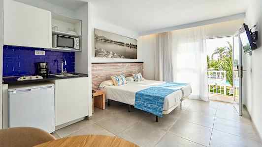 Kuva hotellihuoneesta, jossa on erilliset sängyt, keittokomero ja parveke näköalalla. (Tekoälyn luoma teksti)