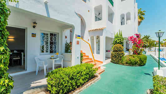 Valkoinen rakennus, jossa terasseja ja vehreä ympäristö. (Tekoälyn luoma teksti)