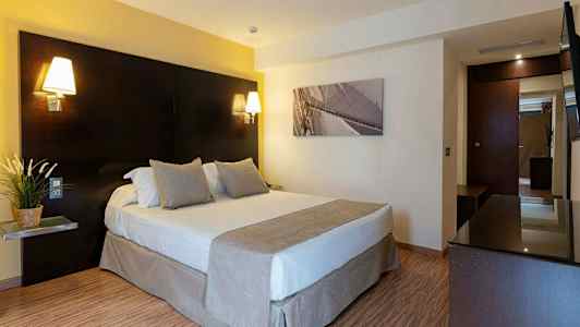 Hotellihuone, jossa on parivuode, yöpöytävalaisimet ja taulu seinällä. (Tekoälyn luoma teksti)