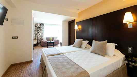 Hotellihuone, jossa kaksi erillistä vuodetta ja oleskelutila. (Tekoälyn luoma teksti)