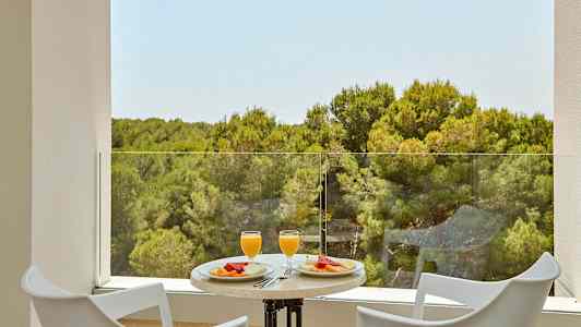 Kaksi tuolia ja pöytä, jossa aamiaiset tarjoillaan näkymällä metsään. (Tekoälyn luoma teksti)