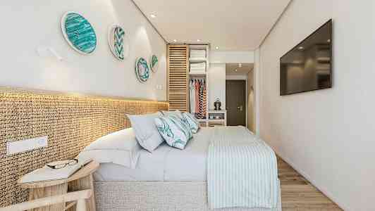 Moderni makuuhuone, jossa parivuode, koristeellisia lautasia seinällä ja avonainen vaatekaappi. (Tekoälyn luoma teksti)