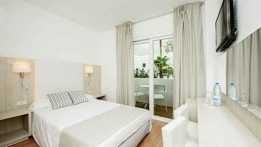 Vaalea hotellihuone, jossa on parivuode, kirjoituspöytä, tuoli ja ikkuna näkymällä parvekkeelle. (Tekoälyn luoma teksti)