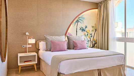 Moderni makuuhuone, jossa on suuri sänky, koristetyynyjä ja seinämaalaus, joka esittää palmuja. (Tekoälyn luoma teksti)