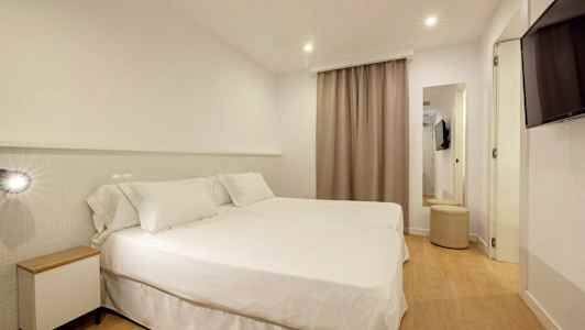 Hotellihuone, jossa on kaksi sänkyä valkoisilla vuodevaatteilla. (Tekoälyn luoma teksti)