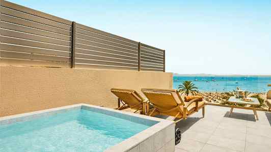 Terassi, jossa pieni uima-allas, aurinkotuoleja ja pöytä merinäköalalla. (Tekoälyn luoma teksti)