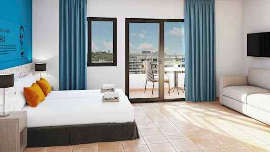 Hotellihuone, jossa on kaksi sänkyä, istuinsarja ja pöytä parvekkeella. (Tekoälyn luoma teksti)