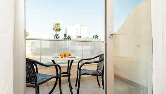 Parveke, jossa on kaksi tuolia ja pöytä, tarjoillaan juomia. (Tekoälyn luoma teksti)