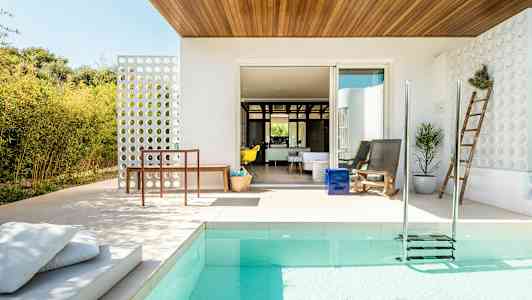 Moderni ulkoterassi, jossa on uima-allas, istuimia ja puutarhakoristeita. (Tekoälyn luoma teksti)