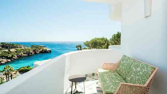 Parveke, jolta avautuu näkymä merelle, jossa näkyy vihreitä kasveja ja kallioita. (Tekoälyn luoma teksti)