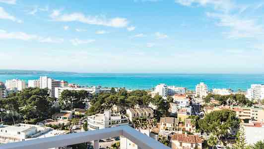 Näkymä rantakaupungista, jossa rakennuksia, puita ja meri taustalla. (Tekoälyn luoma teksti)