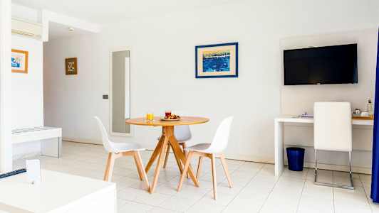 Valoisa huone, jossa on pyöreä ruokapöytä ja tuolit, seinällä televisio ja työpiste tuolin kanssa. (Tekoälyn luoma teksti)