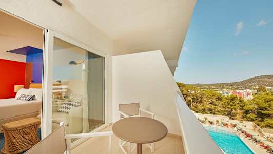 Näkymä parvekkeelta, jossa on pöytä ja tuolit, taustalla uima-allas ja rakennuksia. (Tekoälyn luoma teksti)