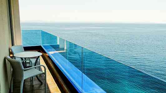 Parveke, jossa kaksi tuolia ja pöytä, jonka suunta on kohti merta. (Tekoälyn luoma teksti)