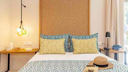 Huone, jossa on sänky kuvioiduilla tyynyillä ja peitolla, sekä yöpöydät ja koristeellisia yksityiskohtia. (Tekoälyn luoma teksti)