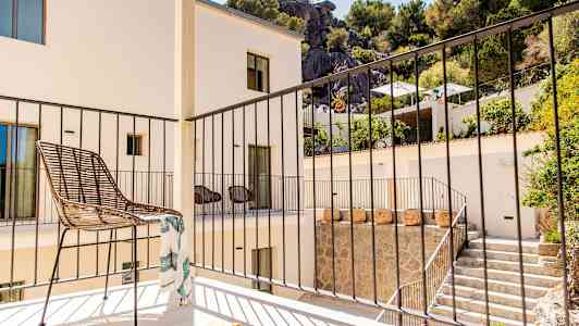 Parveke, jossa on tuoli ja kaide, ympärillä rakennus ja viheralueita. (Tekoälyn luoma teksti)