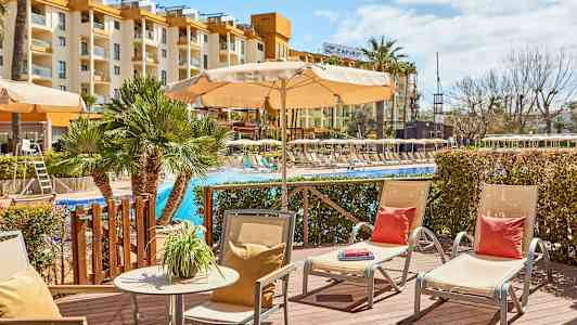 Ulkoilualue uima-altaan äärellä, jossa aurinkotuoleja ja aurinkovarjoja; hotellirakennus taustalla. (Tekoälyn luoma teksti)