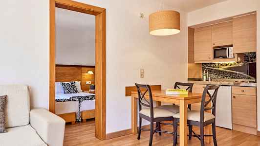 Huone, jossa on keittiö ja ruokapöytä, näkymä makuuhuoneeseen. (Tekoälyn luoma teksti)