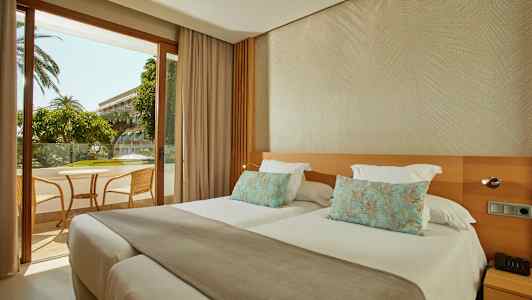 Hotellihuone, jossa on kaksi erillistä vuodetta ja näkymä kalustetulle parvekkeelle. (Tekoälyn luoma teksti)