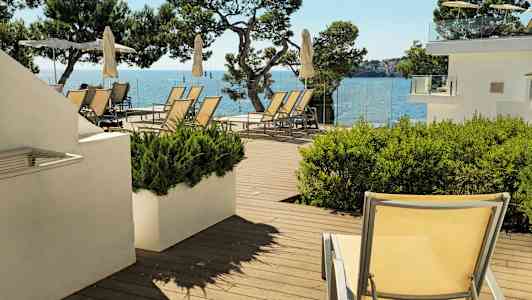 Aurinkotuolit ja aurinkovarjot terassilla, jolta on merinäköala. (Tekoälyn luoma teksti)