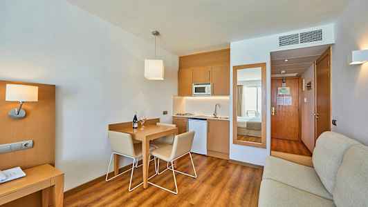 Hotellihuone, jossa on keittiötila ja ruokapöytä. (Tekoälyn luoma teksti)