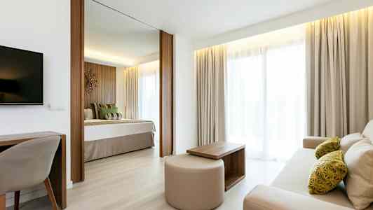 Valoisa ja kutsuva hotellihuone, jossa erillinen makuutila ja oleskelutila. (Tekoälyn luoma teksti)