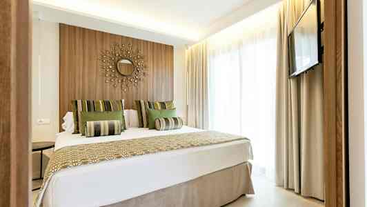 Moderni hotellihuone, jossa parivuode, seinäkoriste ja televisio. (Tekoälyn luoma teksti)