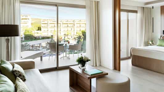 Näkymä hotellihuoneesta parvekkeelle ja ulkoalueelle, jossa on uima-allas ja rakennuksia. (Tekoälyn luoma teksti)