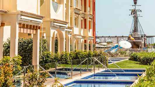 Rakennus, jonka edessä on uima-altaita, ja taustalla näkyy merirosvolaiva. (Tekoälyn luoma teksti)