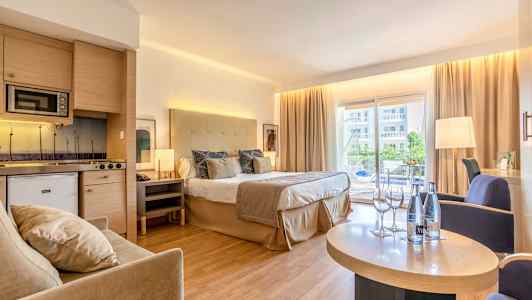 Hotellihuone, jossa parivuode, oleskelutila ja keittiö sekä parveke näkymällä. (Tekoälyn luoma teksti)