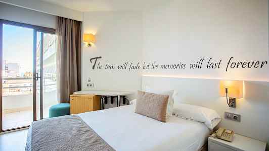 Hotellihuone, jossa parivuode, kirjoituspöytä ja parvekkeen ovi. (Tekoälyn luoma teksti)