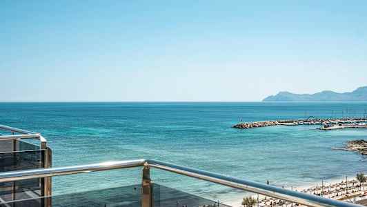 Näkymä parvekkeelta merelle ja rannalle, jossa on aurinkovarjoja. (Tekoälyn luoma teksti)