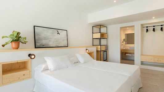 Vaalea hotellihuone, jossa on parivuode ja puisiset sisustusratkaisut. (Tekoälyn luoma teksti)