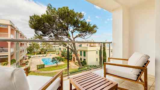 Näkymä parvekkeelta istuinkalusteiden kanssa, sisäpihalle, jossa on uima-allas ja ympäröivät rakennukset. (Tekoälyn luoma teksti)