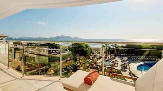 Näkymä parvekkeelta, jossa on aurinkotuoleja ja uima-allas, taustalla ranta ja vuoret. (Tekoälyn luoma teksti)