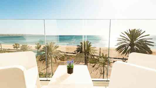 Näkymä parvekkeelta merelle ja rannalle, jossa on palmuja. (Tekoälyn luoma teksti)