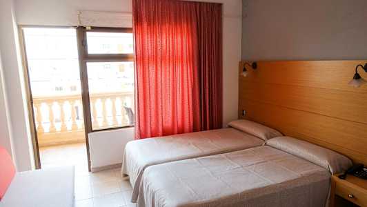 Hotellihuone, jossa kaksi erillistä vuodetta, punainen verho ja parveke. (Tekoälyn luoma teksti)