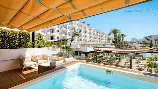 Terassi, jossa uima-allas, istuinryhmä ja näkymä hotellialueelle palmuineen ja rakennuksineen. (Tekoälyn luoma teksti)