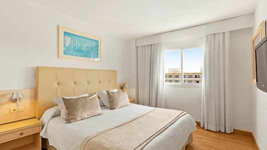 Hotellihuone, jossa on parivuode, ikkuna ja vaaleat verhot. (Tekoälyn luoma teksti)