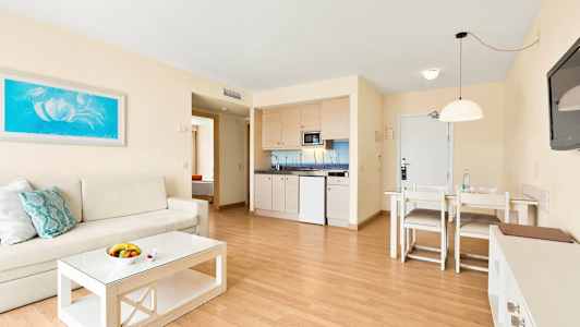 Olohuone, jossa sohva, sohvapöytä, ruokapöytä ja minikeittiö. (Tekoälyn luoma teksti)