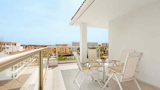 Parveke, jossa pöytä ja tuolit, näkymä ympäröiviin rakennuksiin. (Tekoälyn luoma teksti)